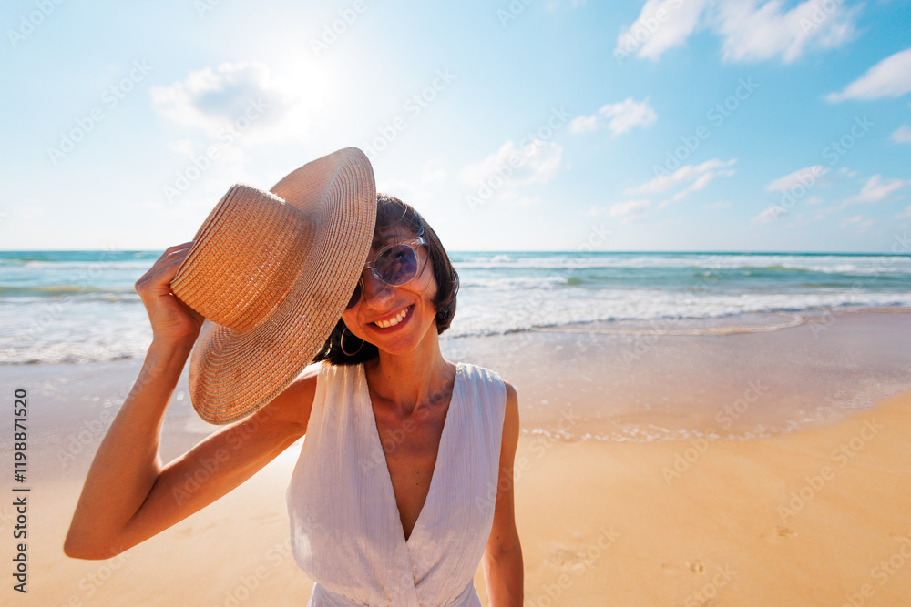 young pretty cheerful girl in a summer dress and hat looks happily at the camera against the backdrop of the sea. young pretty cheerful girl in a summer dress and hat looks happily at the camera against the backdrop of the sea.