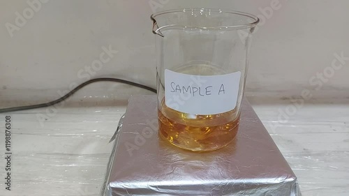 Laboratory Glass Beaker with Orange Liquid Sample A on a Magnetic Stirrer 