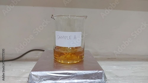 Laboratory Glass Beaker with Orange Liquid Sample A on a Magnetic Stirrer 