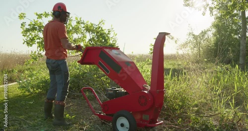 Garden worker using wood chipper shredder machine for making mulch
