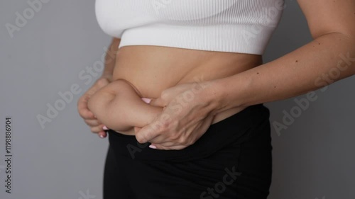 Wallpaper Mural Fat deposits on the abdomen. A young woman holding for belly fat with her hands on a grey background. Overeating, overweight, excess weight, hormonal belly Torontodigital.ca