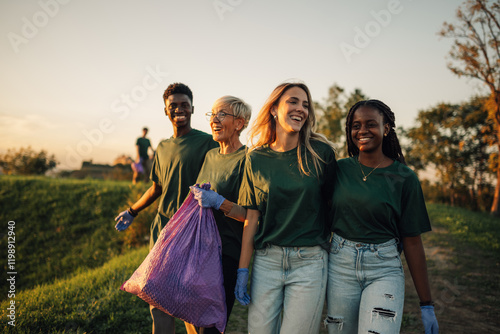 Volunteers carrying garbage bag enjoying teamwork cleaning park