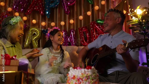 Senior man and senior woman with grandchild having fun at birthday party, Senior couple with child girl at birthday party