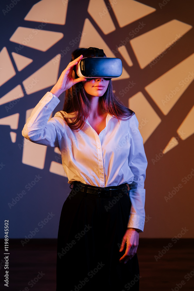 Woman exploring a digital world in virtual reality glasses against a colorful background with abstract shadows Woman exploring a digital world in virtual reality glasses against a colorful background with abstract shadows