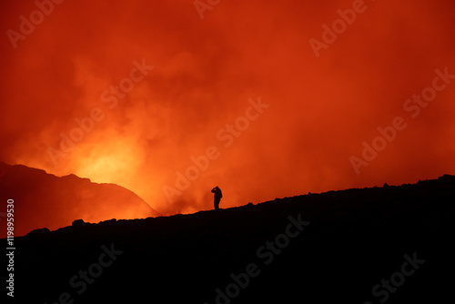 Silhouette of a man watching a volcanic eruption showing how small a person is in such circumstances