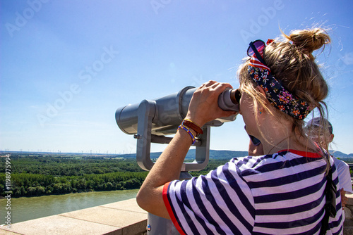 Canvas Print blond girl in a striped T-shirt, portrait, looking through a telescope, from abo