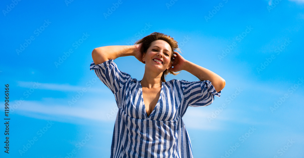 Portrait of beautiful middle aged woman walking against background of blue sky in summertime Portrait of beautiful middle aged woman walking against background of blue sky in summertime