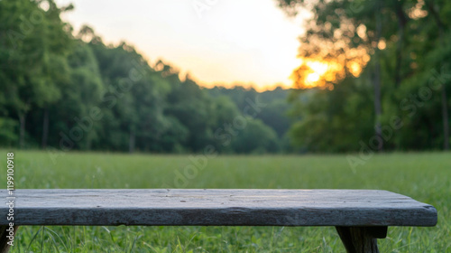 Beautiful sunset view over a tranquil field with wooden bench in foreground