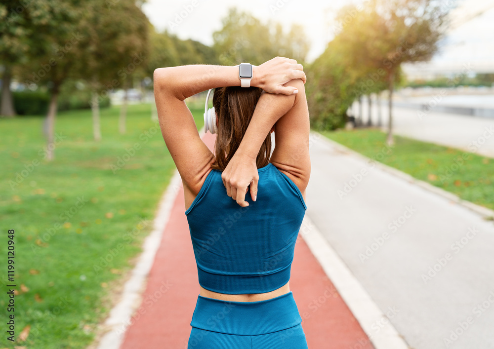 Rear view portrait of female athlete warming up on city street running track Rear view portrait of female athlete warming up on city street running track
