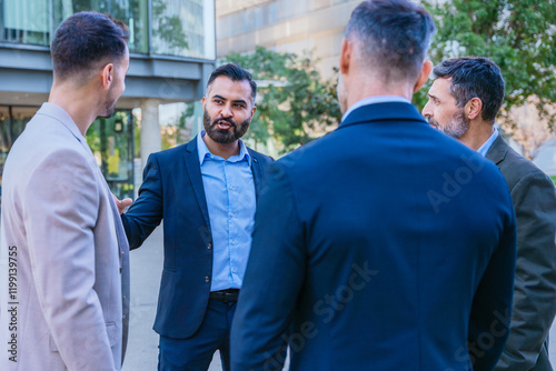 A group of business professionals engaged in a serious discussion outdoors. They are dressed in formal and smart casual attire, with a modern cityscape in the background. photo