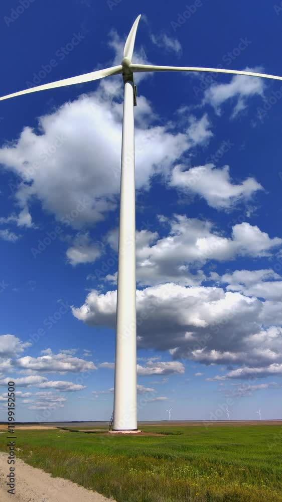 Close-up of a modern wind turbine against a bright blue sky with fluffy clouds Close-up of a modern wind turbine against a bright blue sky with fluffy clouds