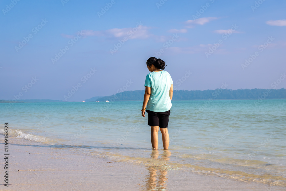 Isolated Girl relaxing at pristine Sandy Beach Shore with rolling waves in Morning Isolated Girl relaxing at pristine Sandy Beach Shore with rolling waves in Morning