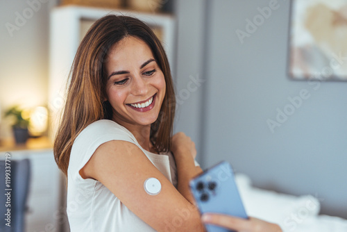 Happy Woman Using Glucose Monitoring System With Smartphone At Home photo