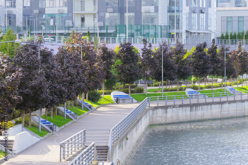 Canvas Print An urban landscape with an embankment, trees, and modern high-rise buildings in the background