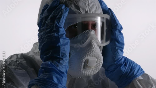 A scientist in PPE holding his head due to a headache, on a white background.