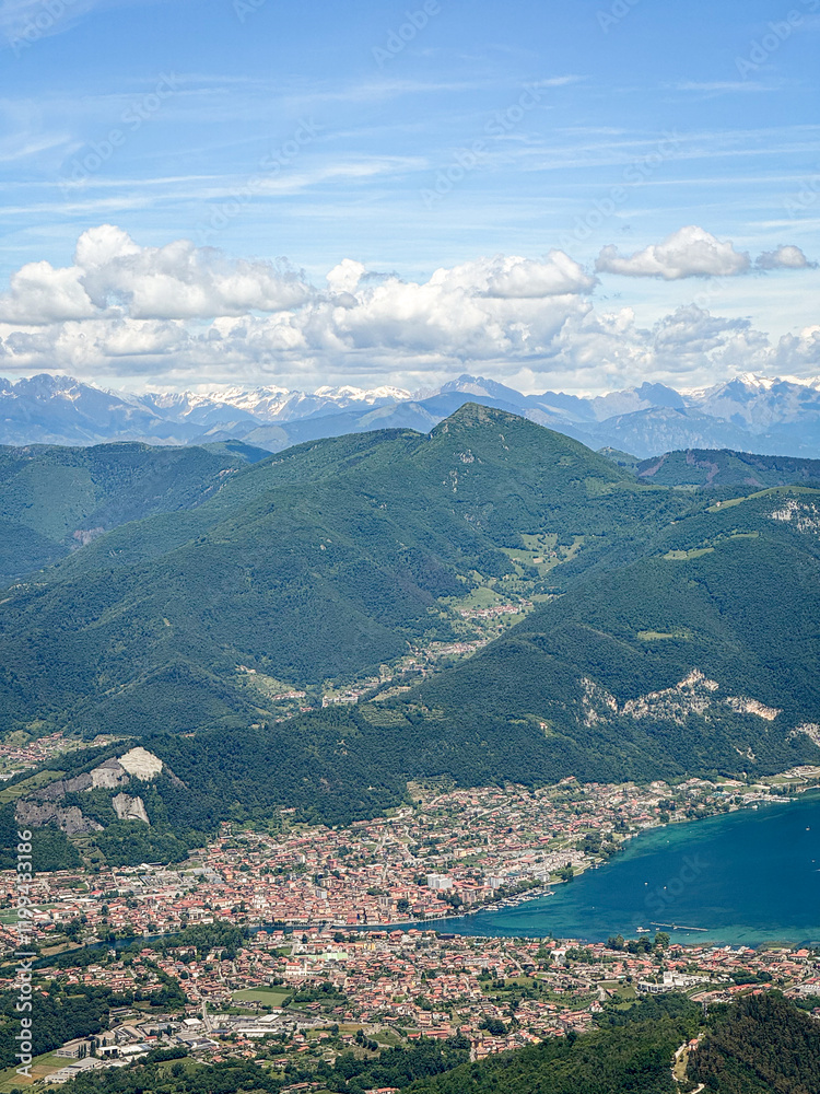 Fototapeta premium Areal view of town Sarnico and turquoise Lake Iseo in Italy and Swiss Alps with snow in mountaintops in the background.
