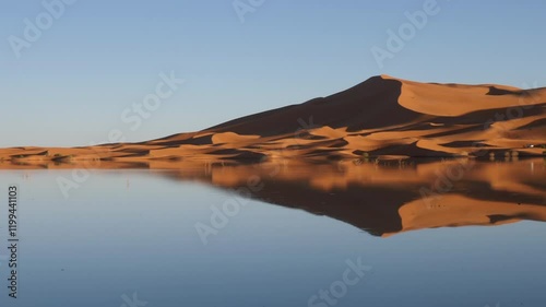 Beautiful Sahara desert sand dunes with reflections in a lake, Erg Chebbi, Morocco. Rain-filled lake after heavy rain. Natural wonder. Serene beautiful landscape and nature background 4k footage. 
