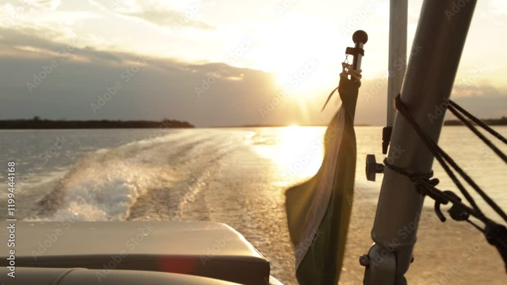 Bandeira tremulando na poupa de barco ao pôr do sol