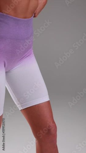 Closeup view of person wearing stylish purple and white gradient athletic shorts during workout session, activewear fashion concept in vertical video