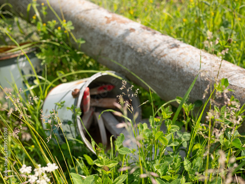 Concept: A paint can with paintbrushes and an old rusty pipe polluting the environment