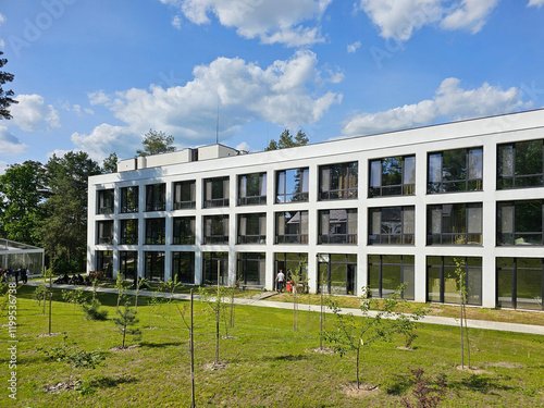 Design of the facade of a modern hotel-type building. A rectangular white architectural structure among a green forest.