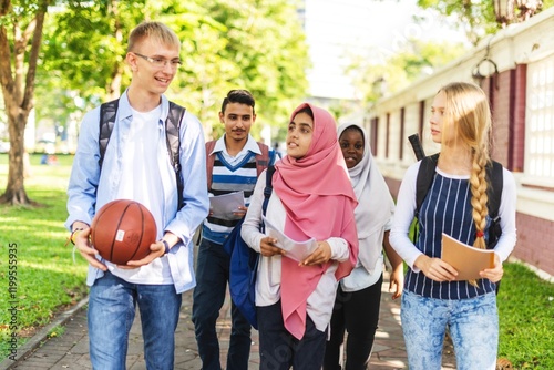 Diverse group of students walking outdoors, holding books and a basketball. Diverse young adults and Muslim girl enjoying a sunny day on campus, smiling and talking. Diverse students walking outdoor