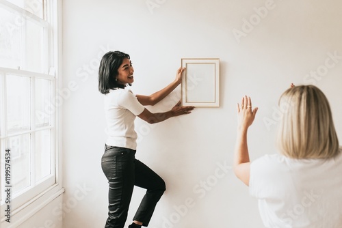 Interior designers styling frames on wall