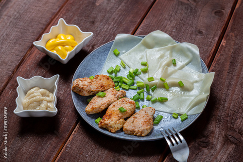 Thin khinkal with meat and herbs and various sauces in a plate on a wooden table photo