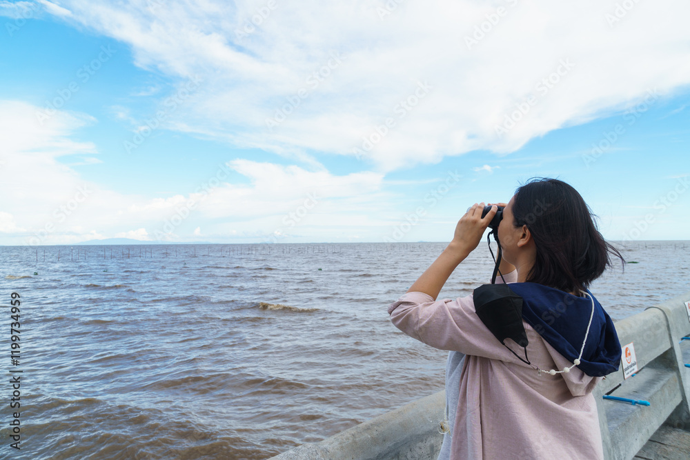 Exploring ocean view with binoculars, woman enjoys nature beauty Exploring ocean view with binoculars, woman enjoys nature beauty
