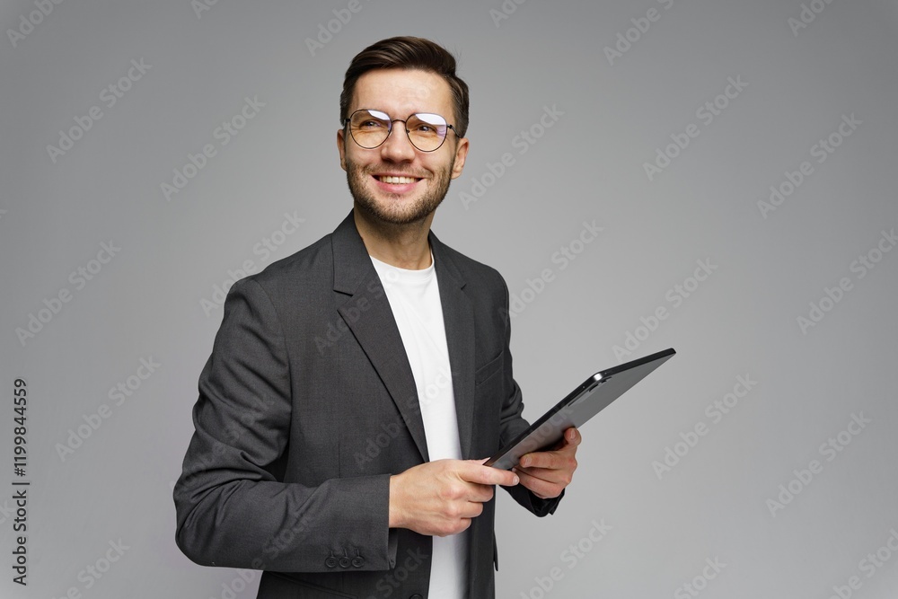Professional man smiling while holding a tablet in a modern studio setting during the daytime Professional man smiling while holding a tablet in a modern studio setting during the daytime