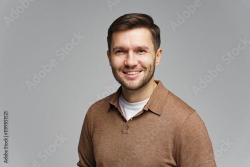 Smiling man with brown shirt and light background posing for a friendly portrait photo