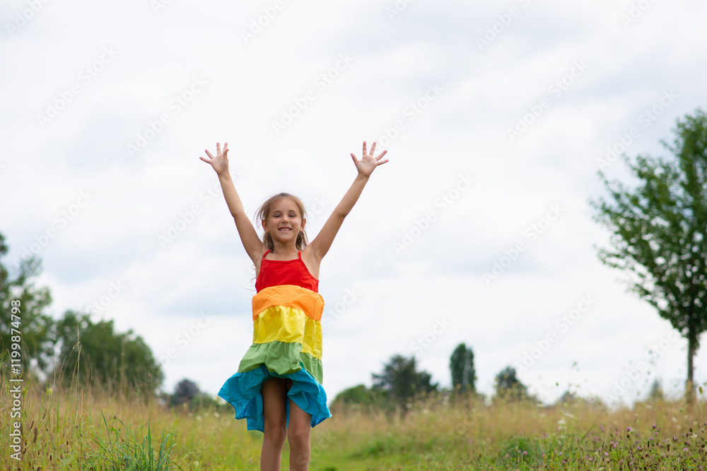 Little girl raises her hands up while jumping on a field on a summer day. Little girl raises her hands up while jumping on a field on a summer day.
