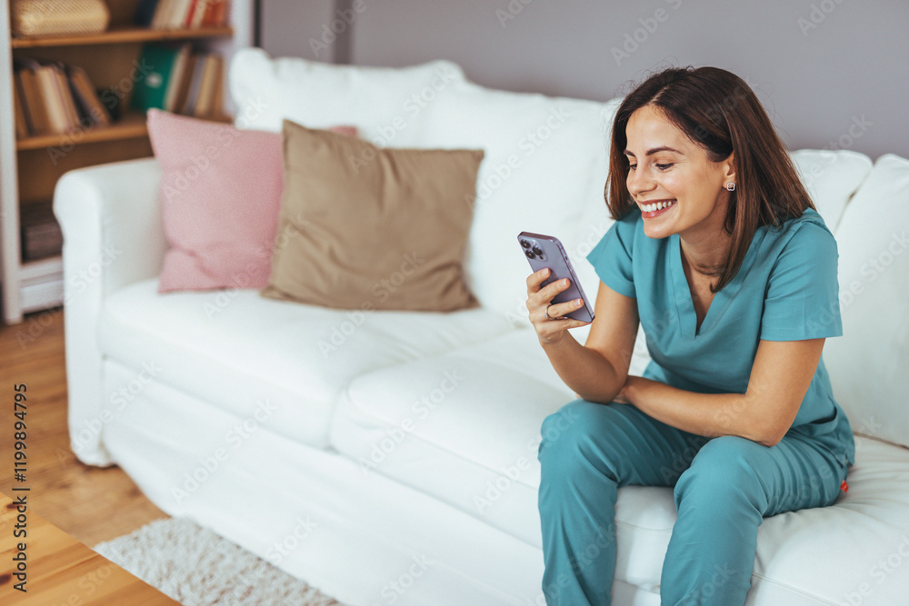 Smiling Woman in Scrubs Relaxing on Couch Using Smartphone at Home Smiling Woman in Scrubs Relaxing on Couch Using Smartphone at Home