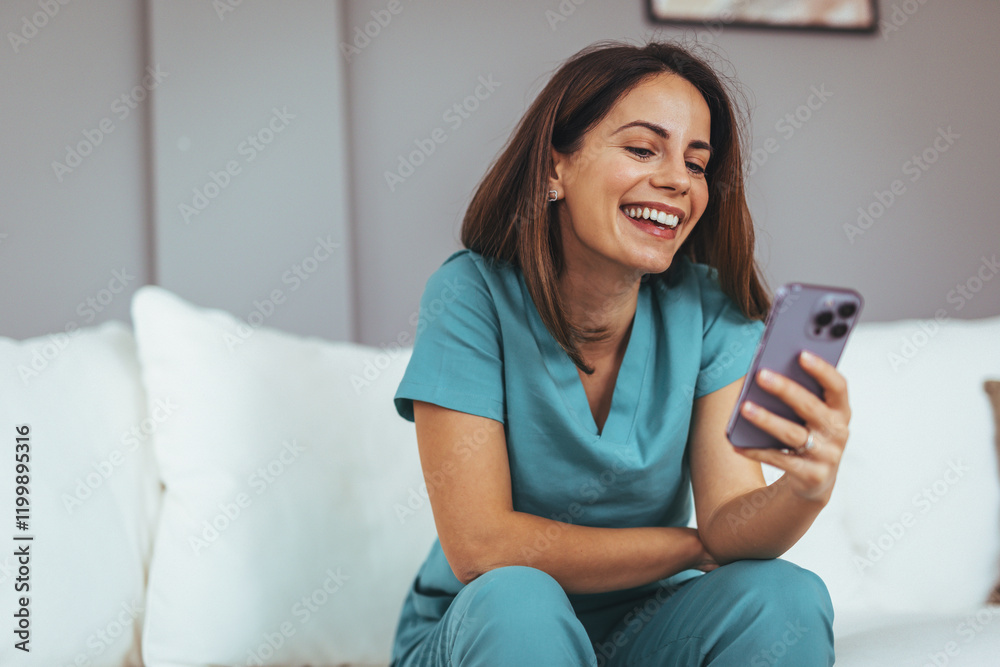 Happy Woman In Scrubs Smiling While Using Smartphone At Home