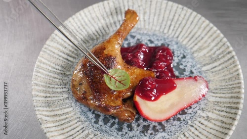 Professional chef carefully placing bright sorrel leaf atop roasted duck leg confit with tweezers, enhancing pear berry sauce presentation on pristine porcelain plate. High cuisine. Chef cooking in