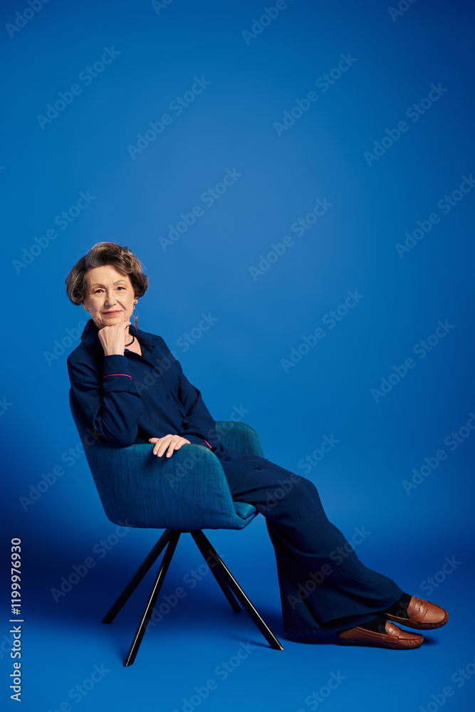 A beautiful woman in her 60s sits gracefully in chic attire, radiating confidence and charm. A beautiful woman in her 60s sits gracefully in chic attire, radiating confidence and charm.