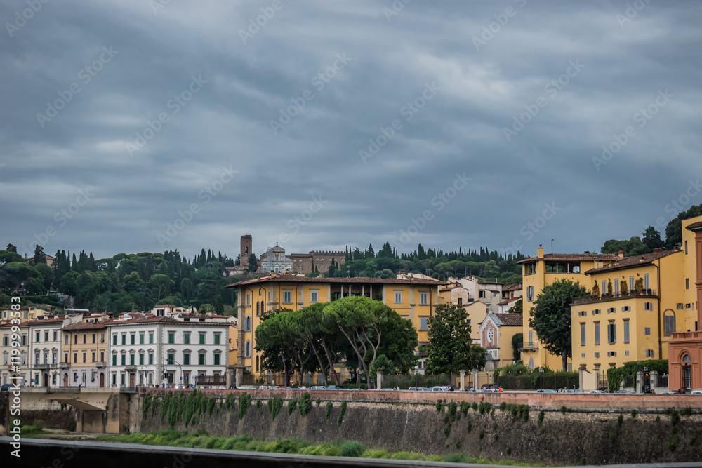 Street and buildings on the bank of the River Arno and Church of San Miniato al Monte on the mountain in the background, Florence ITALY Street and buildings on the bank of the River Arno and Church of San Miniato al Monte on the mountain in the background, Florence ITALY