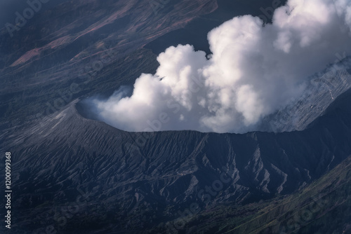 A stunning aerial view of an active Bromo volcano passionately releasing thick clouds of smoke and ash, showcasing natures raw power in a captivating landscape, East Java, Indonesia