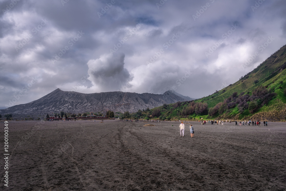 This scene shows a beautiful Mount Bromo and majestic mountains under a cloudy sky, where people enjoy the lovely outdoor landscape, East Java, Indonesia
