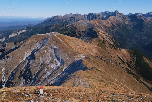 Panorama of Czerwone Wierchy range from around Kasprowy Wierch Peak, Tatras Mountains, Poland. During trekking red trail on sunny autumn day. Little silhouettes of people on trail.