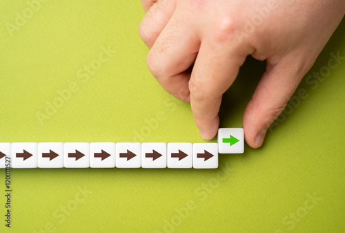 Photos A hand makes a path out of blocks with arrows