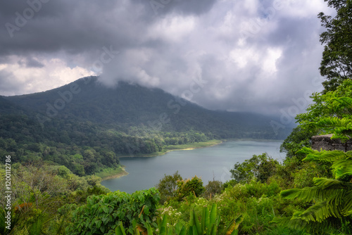 Obraz na płótnie A breathtaking and vibrant landscape showcases a serene mountain lake, beautifully framed by lush, verdant greenery and dramatic, billowing clouds overhead, Bali, Indonesia w salonie