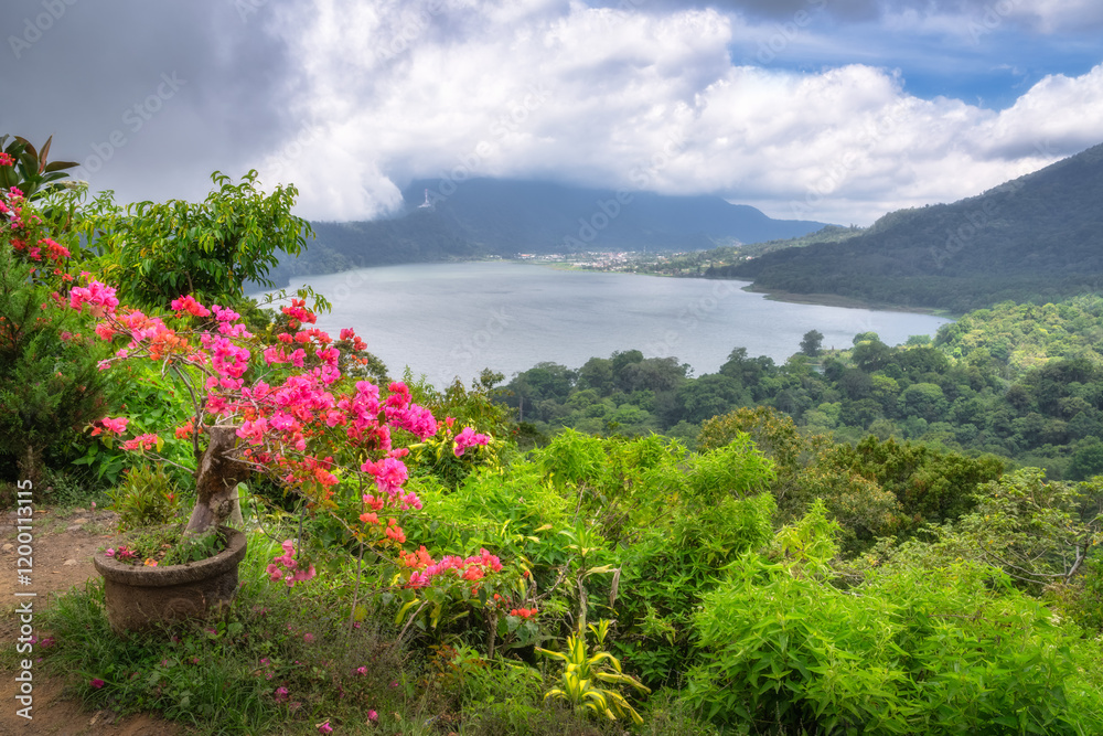 Imagine a breathtaking view of a stunningly serene lake, beautifully framed by lush, vibrant greenery and colorful blooming flowers under a gently cloudy sky, Bali, Indonesia