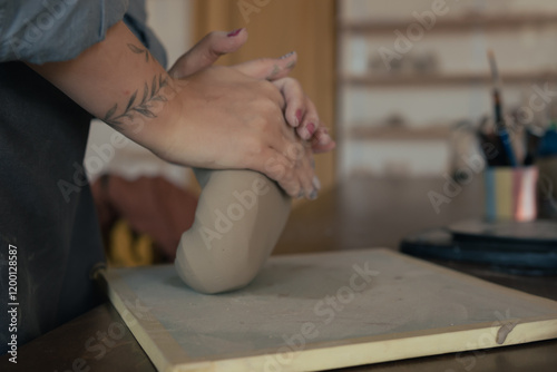 hands of ceramicist knead piece of clay for modeling in pottery workshop