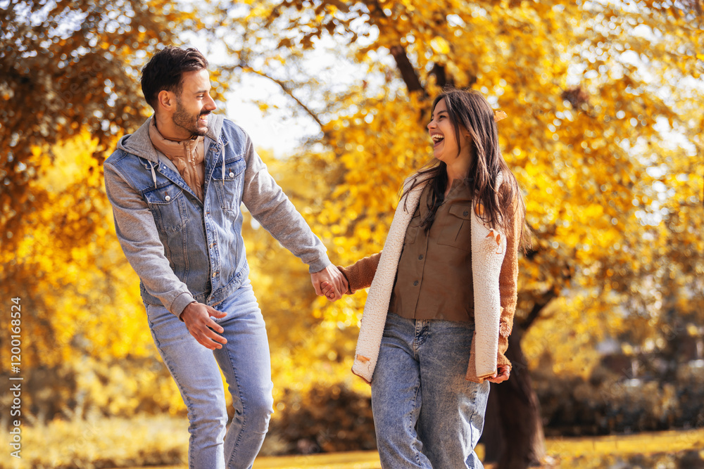 Young happy couple holds hands and runs in the colorful park on a sunny autumn day. Young happy couple holds hands and runs in the colorful park on a sunny autumn day.