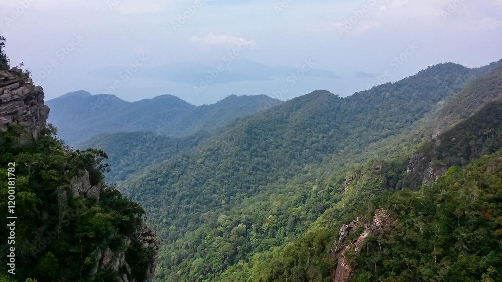 Vast expanse of lush, green mountains stretches into distance, fading into hazy horizon on Langkawi Island, Malaysia. Slopes densely covered with trees. Continuous carpet of greenery. Wilderness