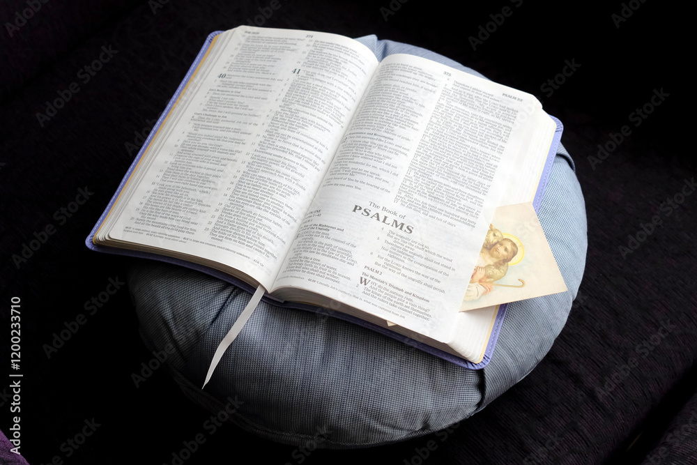 Fototapeta premium Pray at home. Open Bible with a religious image on a cushion.