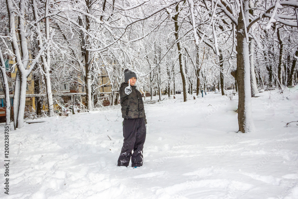 eight-year-old boy standing in the snow, smiling, red cheeks, gloves covered with snow, hat, trees, branches, icicle, frost, winter, fun, walk, rest, weekend eight-year-old boy standing in the snow, smiling, red cheeks, gloves covered with snow, hat, trees, branches, icicle, frost, winter, fun, walk, rest, weekend