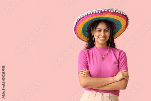 Beautiful young African-American woman in sombrero hat on pink background
