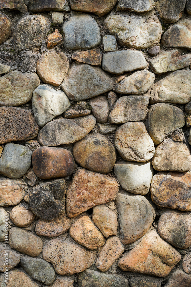 Fototapeta premium Embossed pebble wall for abstract background and texture for interior or exterior design. Beautiful patterns, space for work, banner, wallpaper close up.Vertical.